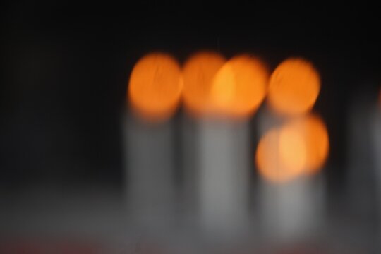 Out of focus burning candles creating a warm bokeh effect against a dark background