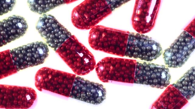 Rows of red and dark gray two-tone iron supplement capsules packed with tiny metallic beads, arranged diagonally in macro close-up