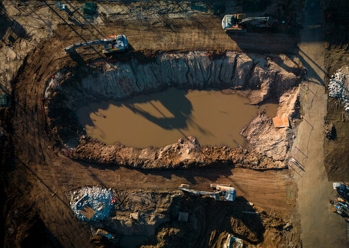 An aerial perspective shows a large excavation site where hydraulic excavators are removing soil to prepare the ground for future construction.