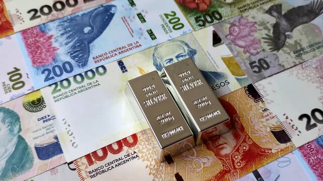 A silver bar, white metal against a backdrop of Argentine money, as a concept for the sales market. A silver bar as a background for your design