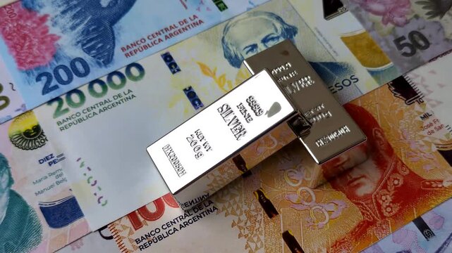 A silver bar, white metal against a backdrop of Argentine money, as a concept for the sales market. A silver bar as a background for your design