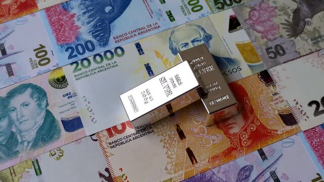 A silver bar, white metal against a backdrop of Argentine money, as a concept for the sales market. A silver bar as a background for your design