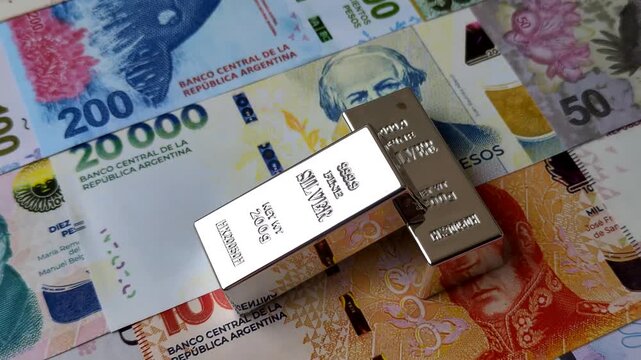 A silver bar, white metal against a backdrop of Argentine money, as a concept for the sales market. A silver bar as a background for your design