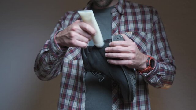 Hands apply polish to a leather boot, demonstrating practical shoe care. The scene shows cleaning, conditioning and preserving footwear with attention to detail and quality.