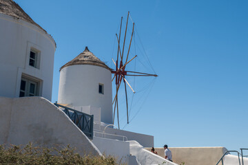 Two iconic Santorini windmills with whitewashed walls under clear blue sky, Greece. © Andrei Tomas