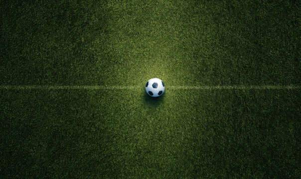 A classic black and white soccer ball placed precisely on a thin white line marking the center of a textured green grass football pitch field