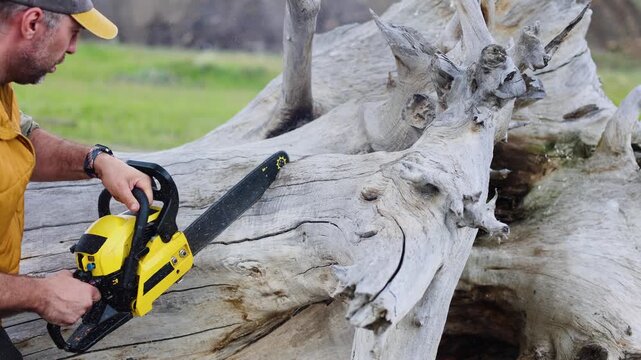 A middle-aged man devotes his time to cutting down a fallen tree with his chainsaw. The process reveals both the challenges and triumphs of outdoor maintenance at its finest. Slow motion 4K footage.