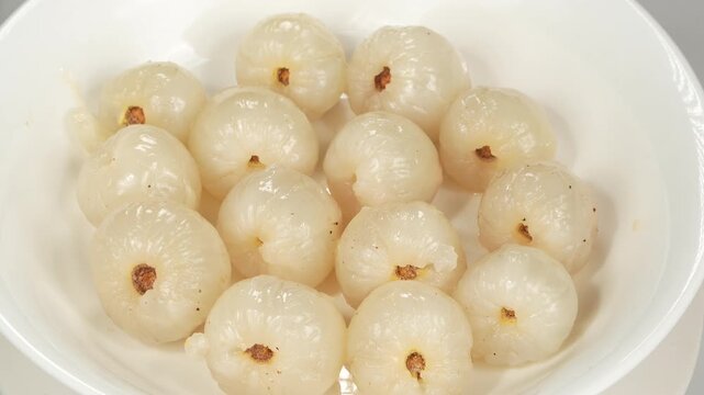 Macro close up of completely peeled fresh red lychee fruits with white juicy pulp on a plate