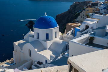 Iconic whitewashed buildings and blue dome above the Aegean Sea, Oia, Santorini, Greece in bright summer daylight. © Andrei Tomas