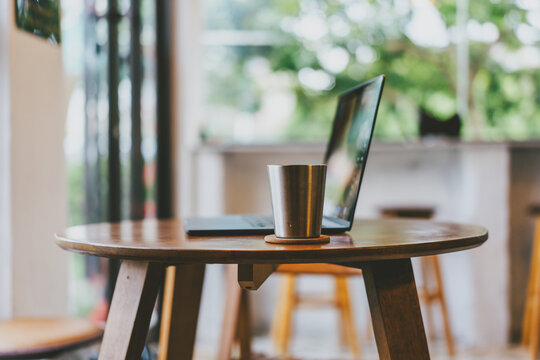Cozy caf&eacute; corner in Tokyo, Japan &mdash; wooden table with laptop and metal cup near large window