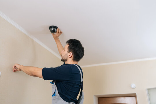 Security technician mounting dome cctv camera on ceiling, ensuring professional installation and enhanced monitoring for residential or commercial property protection and safety.