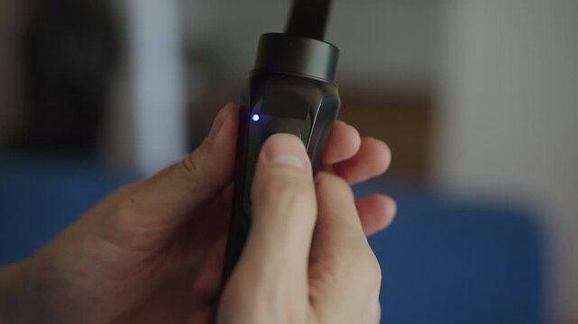 Male hands holding professional three axis gimbal, turning it on and calibrating device for smooth video shooting. blue and red indicator lights blink during setup process, close-up, slow motion