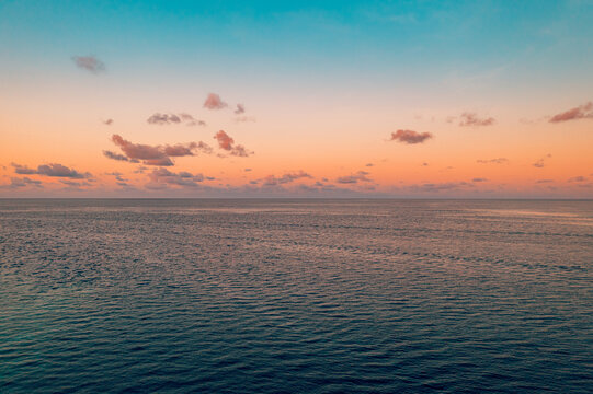 Beautiful aerial calm ocean pastel sunset horizon. Dreamy tropical sea glowing soft evening light. Serene minimal seascape, peaceful summer vacation travel meditation luxury escape nature wallpaper