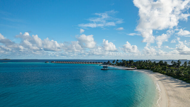 Stunning aerial Maldives beach overwater villas turquoise. Curved white sand lagoon luxury resort paradise. Idyllic summer vacation travel escape, peaceful exotic island holiday drone view
