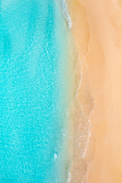 Calm vertical summer seascape beautiful waves, blue ocean water in sunny day. Top view from drone. Sea aerial view, amazing tropical nature background. Gorgeous island beach sand sunset light idyllic