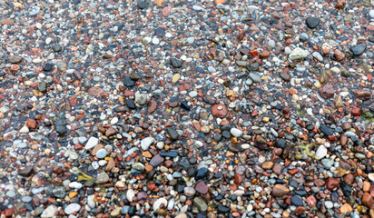 Many small colorful stones on a beach shore. Close up of smooth pebbles and gravel texture. Natural background for calming meditation or wallpaper design. Earth tone mineral surface. © Anton Dios