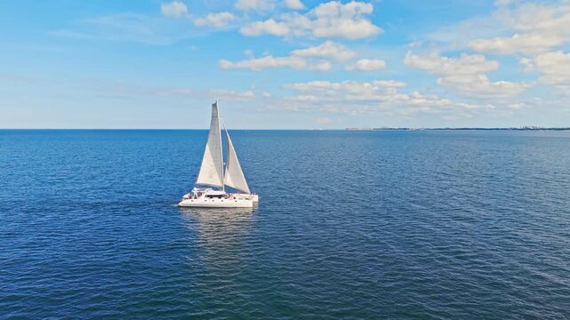 Side view of luxury sailing catamaran gliding across Baltic Sea under blue sky