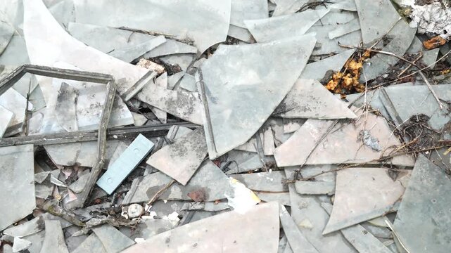 Broken glass fragments scattered on the ground with debris and urban waste, abstract texture of destruction and urban decay