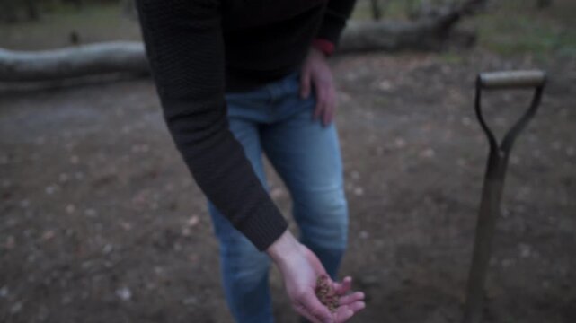 A man says goodbye to his pet, burying it in the forest. He digs a grave with a shovel and sprinkles favorite food as a final ritual. A heartbreaking scene of mourning and loss of a loyal friend
