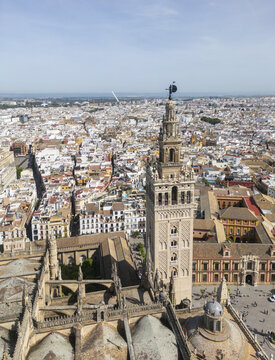 Aerial view of La Giralda bell tower rising above the historic rooftops and urban landscape of the city center in Sevilla, Andalucia, Spain.