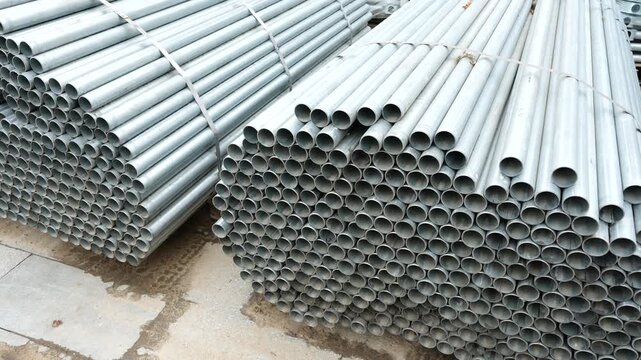 Stacked steel pipes stored in outdoor construction yard showing industrial building materials for infrastructure, plumbing and utility engineering systems