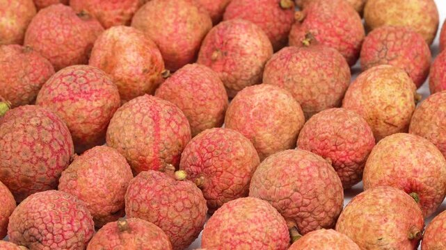 Full frame macro texture of neatly arranged fresh red lychee fruits rotating