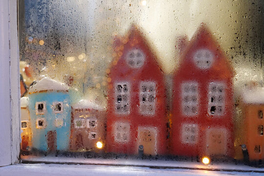 Colorful houses and garland in the window of Christmas toy store