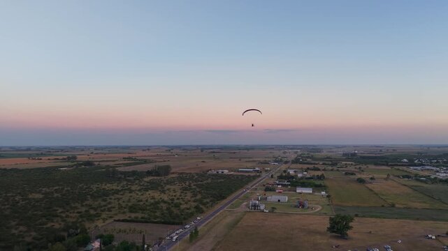 Persona volando en paramotor sobre el campo al atardecer, turismo de aventura, deporte extremo y vuelo recreativo