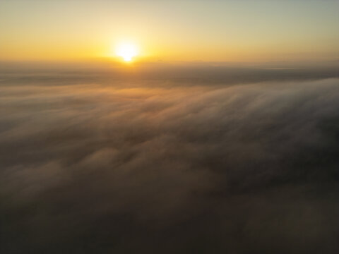 Aerial view of a golden sunrise illuminating a thick layer of clouds over the landscape near El Cotillo, Canary Islands, Spain.