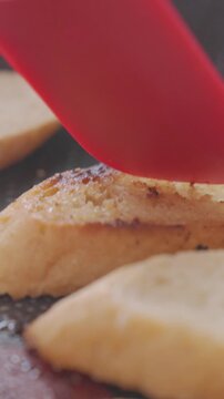 Hand flips slice of bread in frying pan with a spatula in closeup. Concept of cooking and toasting bread