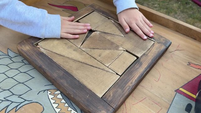 Hands solving wooden puzzle game, tabletop brain teaser close up