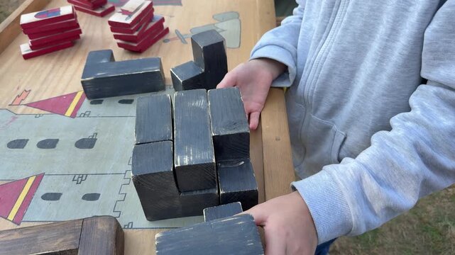 Children stacking wooden blocks in tabletop game, hands close up
