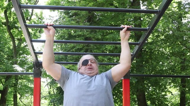 Man With Eye Patch Completes Determined Pull-ups At Outdoor Park Gym