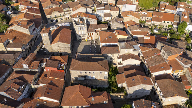 Aerial view of Igrexa de Santiago surrounded by historic stone buildings with terracotta rooftops in the old town of Allariz, Ourense, Spain.