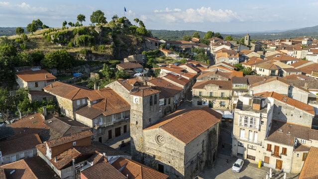 Aerial view of Igrexa de Santiago surrounded by historic stone buildings with terracotta rooftops in the old town of Allariz, Ourense, Spain.
