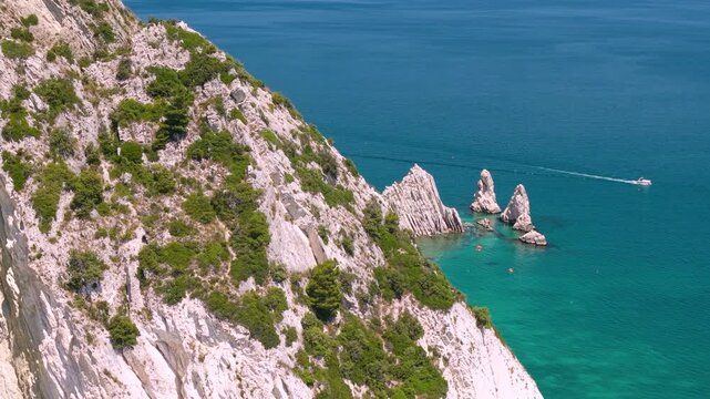 Sirolo Marche Italy 4k drone 70mm telephoto view of Two Sisters iconic beach Due Sorelle. Sideway parallax reveal flight from white cliff over rocky limestone stacks in tropical turquoise sea water