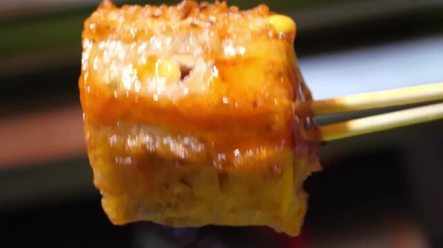 close-up cross-section view of a freshly fried Korean fish cake bar (hotbar or eomuk-bar) wrapped around a juicy pork sausage on a stick, a popular street food snack.