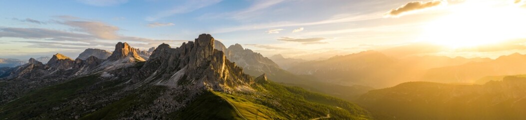 Fototapeta premium Dramatic sunset panorama of Ra Gusela at Passo Giau in the Italian Dolomites. Rugged limestone cliffs, golden sun rays and breathtaking alpine scenery under colorful clouds.