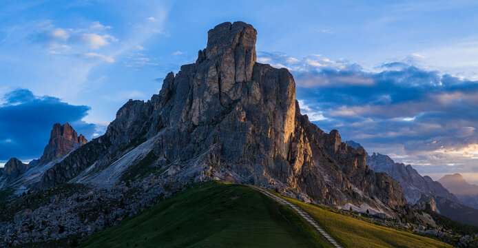 Dramatic sunset panorama of Ra Gusela at Passo Giau in the Italian Dolomites. Rugged limestone cliffs, golden sun rays and breathtaking alpine scenery under colorful clouds.