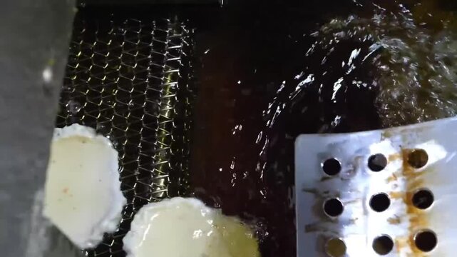 close-up high-angle footage of homemade Korean fish cakes (eomuk/odeng) being prepared and fried. The video shows the white fish paste being shaped and cooked in hot oil until golden brown, a staple o