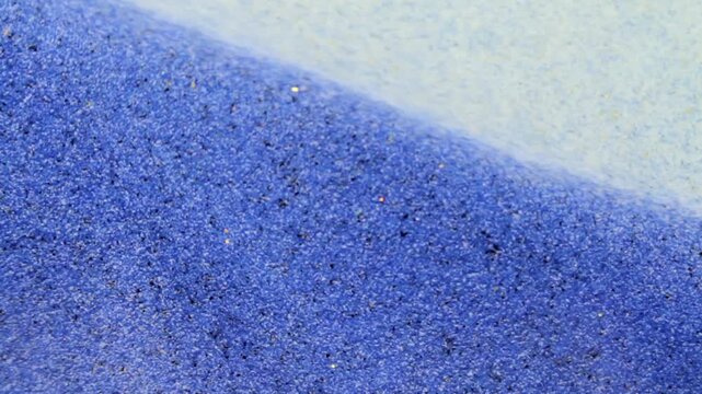 Artistic macro footage of an hourglass with colored sand particles in motion, representing timing, balance, efficiency and the measurable flow of time.