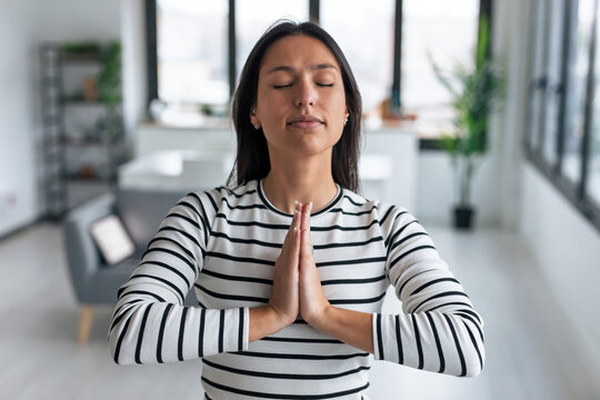 Kind woman doing yoga and meditation in the living room at home