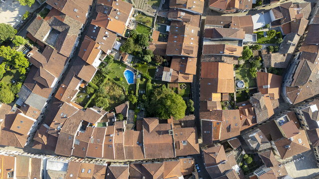 Aerial view of the historic town featuring dense terracotta rooftops, narrow streets, and a private garden with a swimming pool in Allariz, Province of Ourense, Spain.