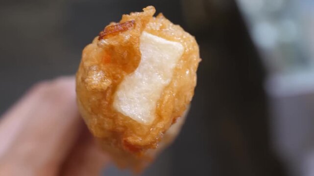 A detailed close-up shot of a traditional deep-fried Korean fish cake, known as Eomuk or Odeng. This popular street food snack features a golden-brown, crispy fried batter with a savory and chewy fish