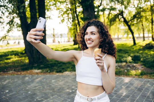 Happy young woman creating selfie video with ice cream