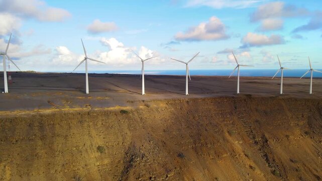 Aerial shot of a row of wind turbines near the ocean in Hawaii