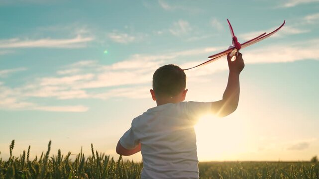 Child plays with toy airplane, sky. Happy boy runs with toy airplane field in rays setting sun. Child aviator dreams flying becoming pilot. Little boy wants become pilot astronaut. Slow motion