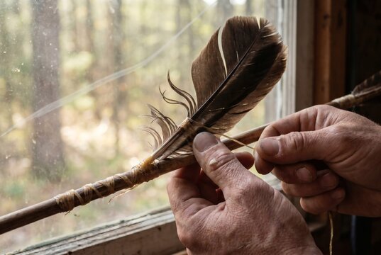 Close Up of Craftsman Hands Binding Feather Fletching to Wooden Arrow Shaft with Sinew Traditional Archery Craft Concept