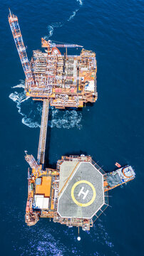 Aerial view of an offshore oil platform with a helipad and industrial cranes situated in the deep blue waters of the Adriatic Sea, Croatia.