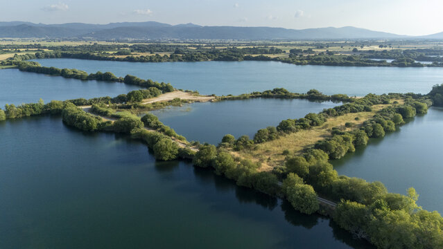 Aerial view of the Extraccion de aridos Lima S.L gravel extraction site with water reservoirs, lush vegetation, and rolling hills in Vilarino das Poldras, Ourense, Spain.